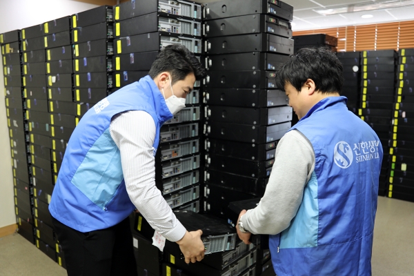 신한생명 직원이 소외아동을 위한 온라인 강의용 PC를 지원하기 위해 컴퓨터 본체를 정리하고 있는 모습