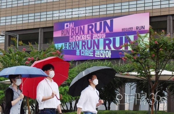 ] 3일 우산을 쓴 시민들이 교보생명 '광화문글판 특별편'이 내걸린 광화문 교보생명빌딩 주변을 걷고 있다. 교보생명은 코로나19 사태 장기화로 지친 이들의 마음을 위로하기 위해 방탄소년단(BTS)의 노래 가사가 담긴 '광화문글판 특별편'을 선보였다. '광화문글판 특별편'에 담긴 노래는 2015년 발매된 '런(RUN)'으로, 불안하고 위태로운 현실 속에서도 앞을 향해 달려나가는 청춘의 에너지를 담았다.