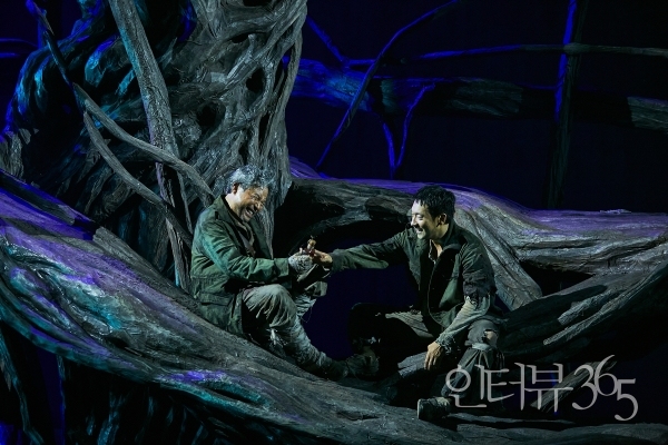 2023 연극 '나무 위의 군대' 공연 사진. 나무 위의 삶에서 일상의 리듬을 발견한 '상관(김용준)'과 '신병(손석구)'은 적군이 버린 쓰레기를 뒤져 필요한 물건들을 조달한다.