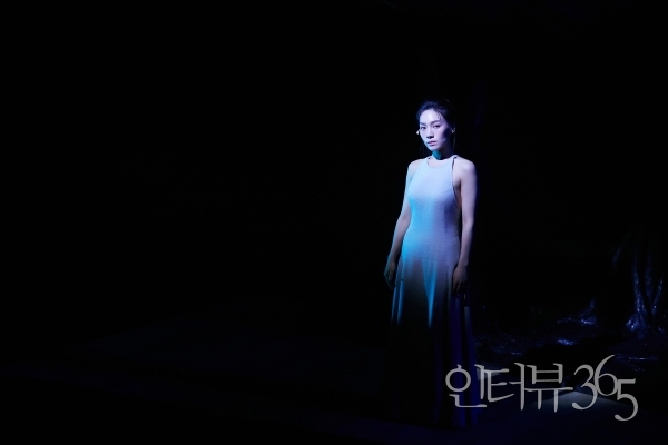 2023 연극 '나무 위의 군대' 공연 사진. 신비한 존재인 '여자(최서희)'는 시종일관 무대 위에 머무르며 극 중 인물(신병의 애인, 상관의 아내)을 연기하거나 관객들에게 인물들의 속내 및 배경을 설명한다.