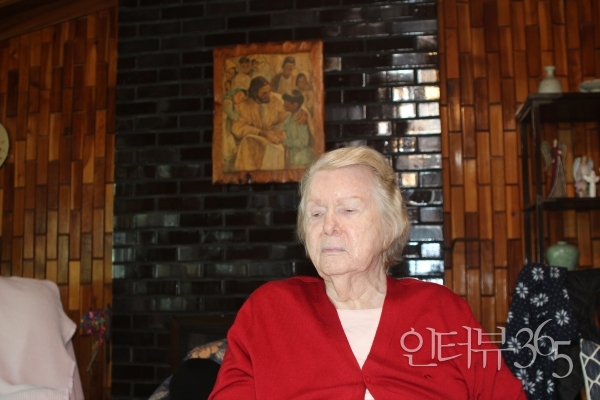 미국 위스콘신주에 살고 있는 조카가 제작한 예수가 어린이들을 돌보고 있는 목판화 작품을 배경으로 포즈를 취한 백제인 여사
