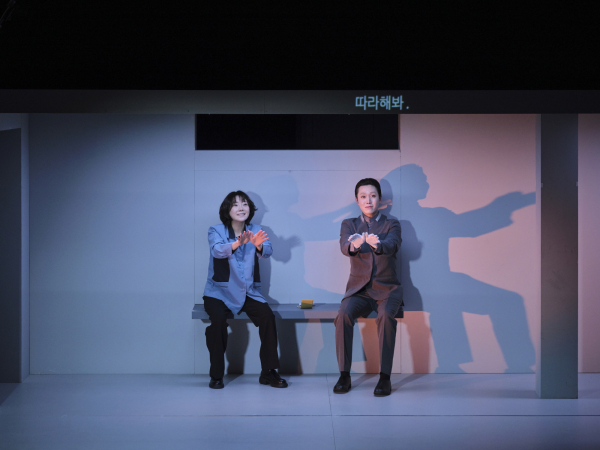 연극 '뼈의 기록' 공연 사진. 손으로 나비 문양을 만들어 보여주는 '모미(강혜진)'와 따라하는 안드로이드 장의사 '로비스(장석환)'./사진 제공=예술의전당, 할리퀸크리에이션즈